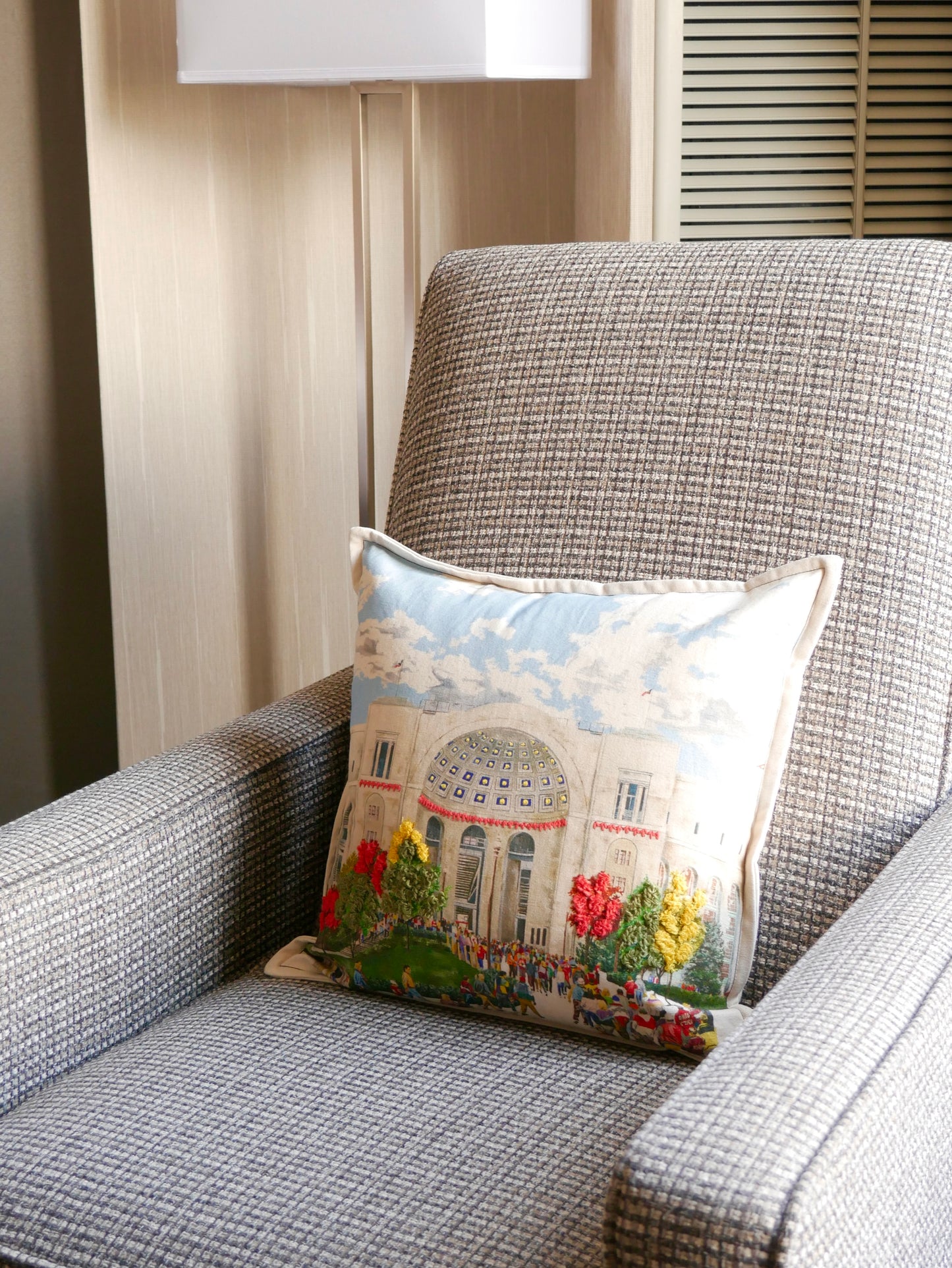 Decorative pillow with a scenic design on a gray armchair